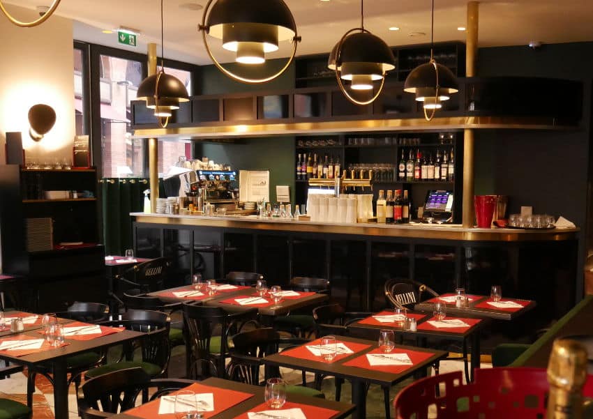 Comptoir noir avec décoration laiton dans salle de restaurant avec tables noires, dessus table rouge, dessus comptoir étain, suspentes de GIO PONTI