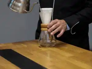 Table en chêne pour la préparation du café. Une fiole en verre posée dessus pour la préparation du café.