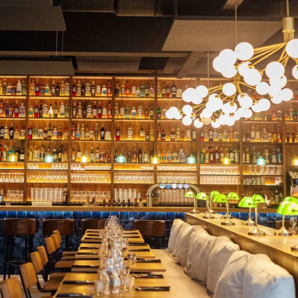 Arrière bar lumineux et multicolore en bois vieilli avec jeu de lumières sur les bouteilles et verres.