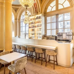 bar avec long comptoir et rayonnage rétro-éclairé dans salle avec aracades, colonnes et grandes portes vitrées cintrées