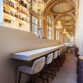 interieur d'un brasserie d'époque avec une enfilade de colonnes et d'arcades. Bar moderne avec rayonnage rétro-éclairé au premier plan.