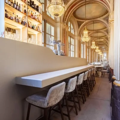 Bar devant l'enfilade de colonnes, d'arcades et de lustres d'époque.