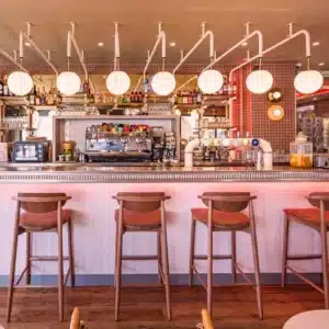 Gros plan sur le comptoir du bistrot Totem avec lumière LED orangée et rangée de tabourets