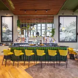 Photo du bar avec chaises hautes jaunes et décor végétal.
