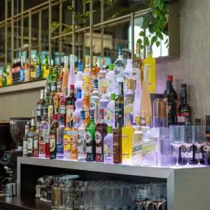 Arrière-bar de la brasserie Quatre 45 à Montauban avec étagères rétro-éclairées pour les bouteilles et fond miroir.