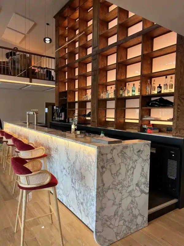 Bar moderne avec comptoir en marbre de carrare, rayonnage rétro-éclairé toute hauteur