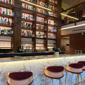 Comptoir en marbre blanc de carrare avec chaises hautes rouge devant et arrière bar toute hauteur avec éclairage LED