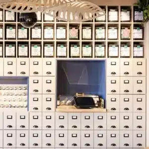 Détail meuble de rangement beige avec tiroirs d'apothicaire et niche boites à thé