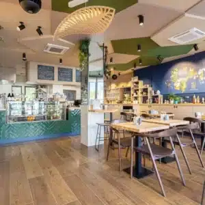 Salle principale du coffee shop ACAPELLA à Toulouse avec espace dégustation, comptoir en faïence verte, meubles de rangement et présentation a l'arrière plan