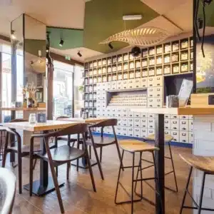 Intérieur salle coffee shop ACAPELLA avec porte d'entrée, meubles de rangement sur mesure et espace dégustation avec tables et chaises