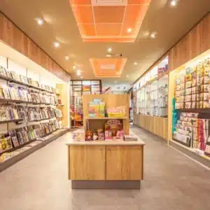 Vue de l’espace presse du Tabac Presse TOTEM à Plaisance-du-Touch, agencé par Aranda-Mas avec rayonnages sur mesure, mobilier central et éclairage chaleureux.