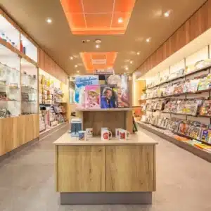 Vue de l’espace presse de l'établissement multi-services TOTEM à Plaisance-du-Touch, avec rayonnages sur mesure, mobilier central et éclairage chaleureux.