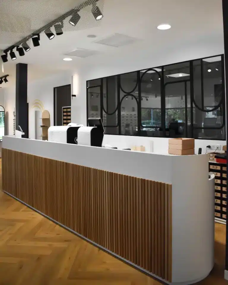 Comptoir blanc avec angles cintrés et façade en tasseaux de bois clair verticaux