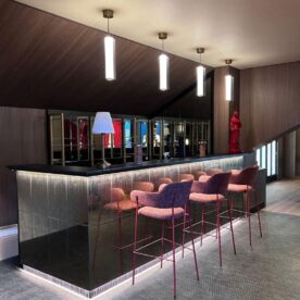 Bar sur mesure du salon VIP, La Vierge Rouge au Stade Toulousain, avec granit noir, façade miroirs rétroéclairés et chaise haute rouges.