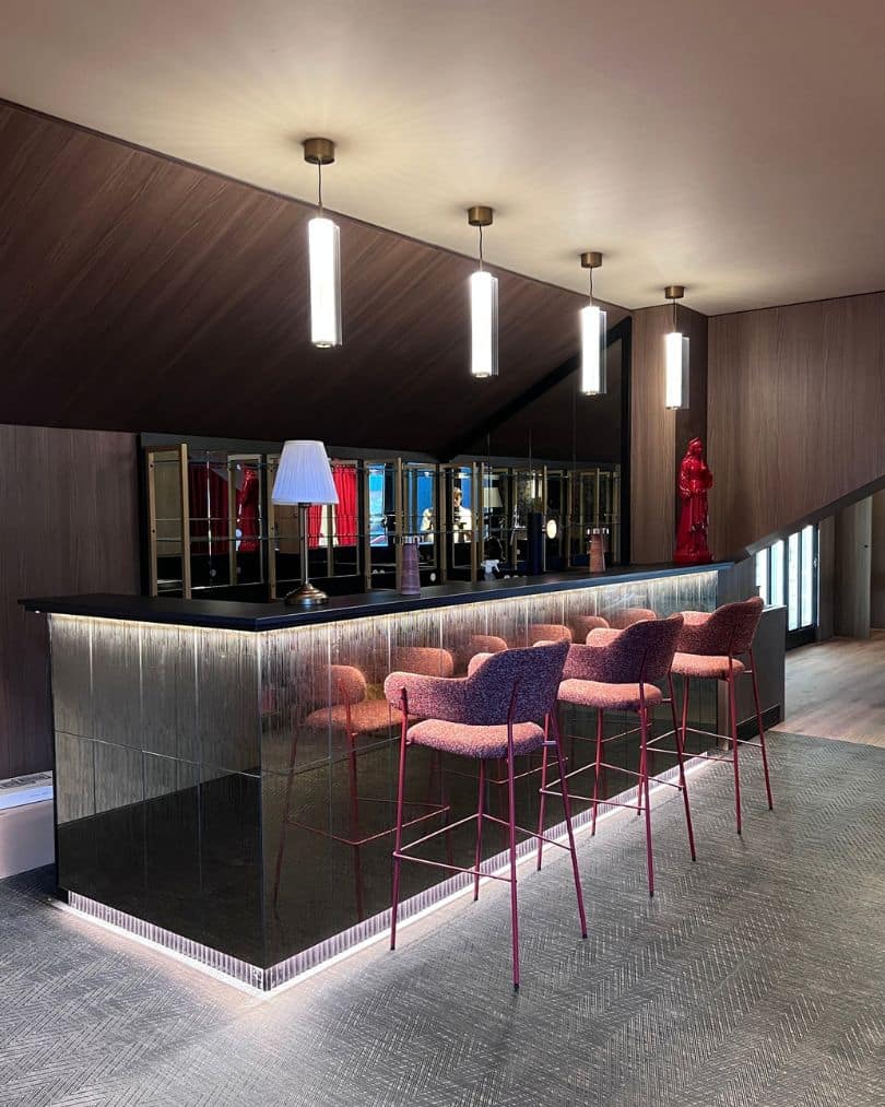 Bar sur mesure du salon VIP, La Vierge Rouge au Stade Toulousain, avec granit noir, façade miroirs rétroéclairés et chaise haute rouges.
