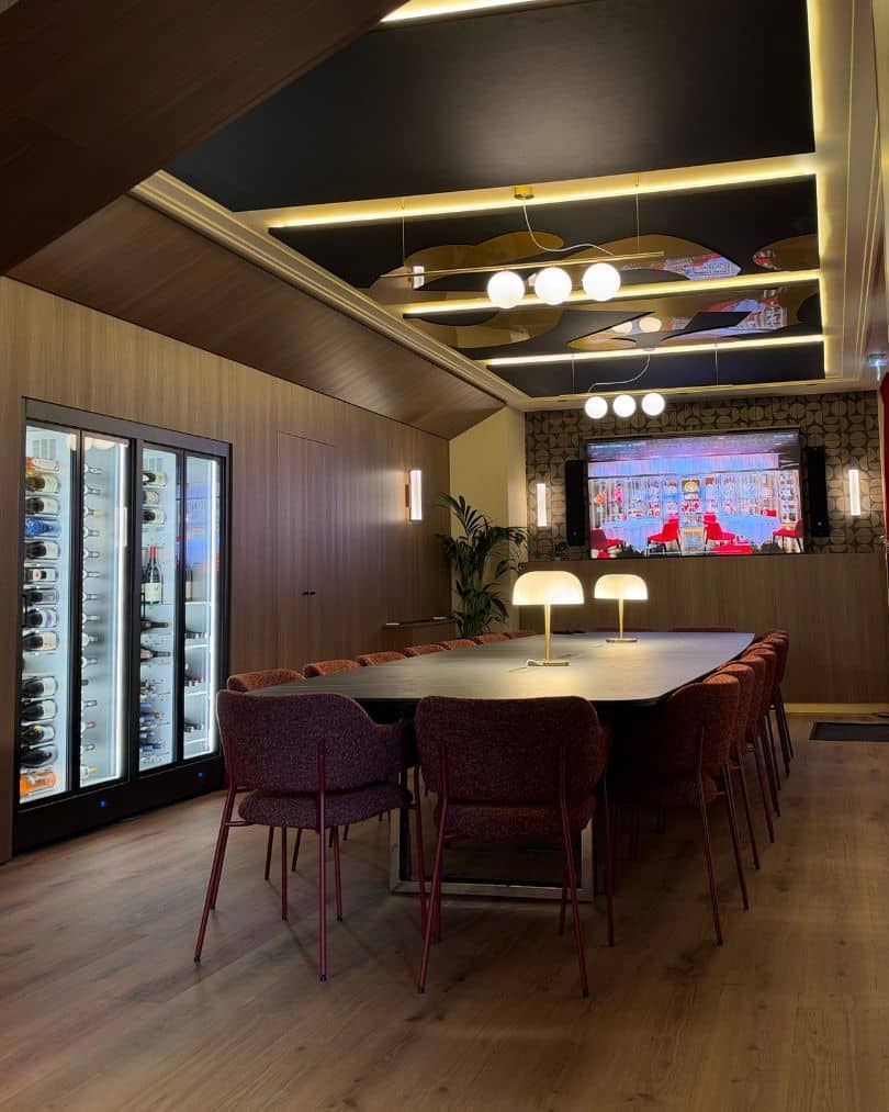 Salle de réunion VIP avec grande table, cave à vin intégrée, habillages en bois et grand écran au Stade Toulousain.
